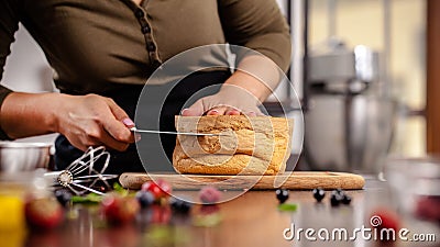The pastry chef prepares a biscuit cake in the home kitchen or in a restaurant. The concept of the process of making cakes Stock Photo