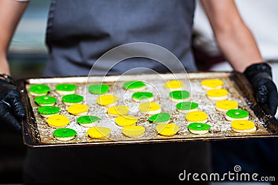 The pastry chef shows raw colored eclairs rings on a baking sheet Stock Photo