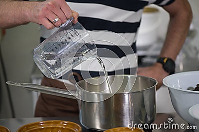 Pastry pouring water into a chocolate mixture Stock Photo