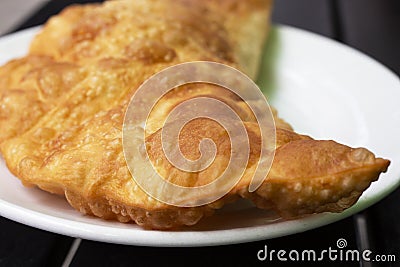 pasty with beef and pork on a white plate, decorated with vegetables and herbs on a wooden table Stock Photo
