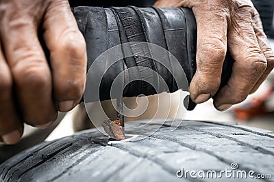 Patch a tyre,Hands of old man patching puncture tubeless car tire,repair rubber surface that have been stabbed by nails,recap on Stock Photo