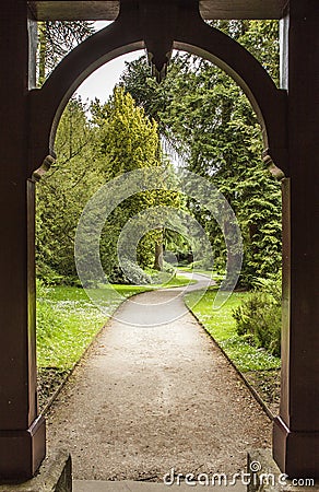 Path through arch leading to formal gardens Stock Photo