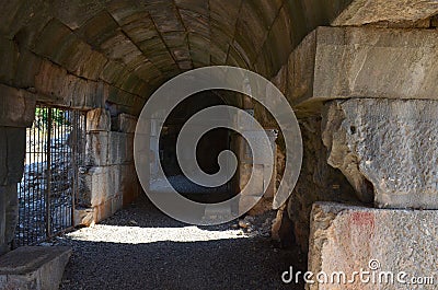 Path through a dark curved arched tunnel in old stone ruins Stock Photo