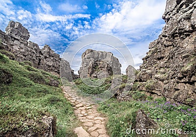 Path inside of the rift valley between Eurasian and North American tectonic plates in the Canyon Almannagja under blue cloudy sky Stock Photo