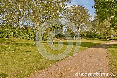 a path leading into a park with two soccer goals Stock Photo