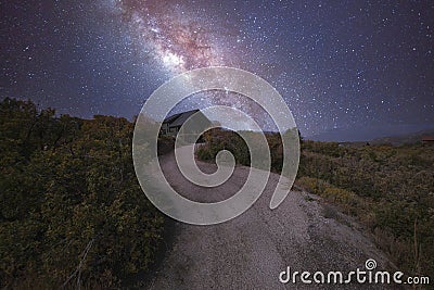 Path in the middle of a shrubland leading to a house under an aesthetic composite milky way Stock Photo