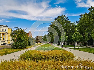 Pathways with colorful path with flowers and bushes between at sunny cloudy day Stock Photo