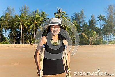 Patient asian woman using crutches support broken legs for walking at the beach,Physical therapy concept Stock Photo
