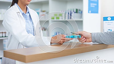 Patient buying medicine from pharmacist at the pharmacy store. Customer receives prescription medication at the chemist Stock Photo