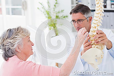 Patient looking at anatomical spine while doctor explaing her Stock Photo