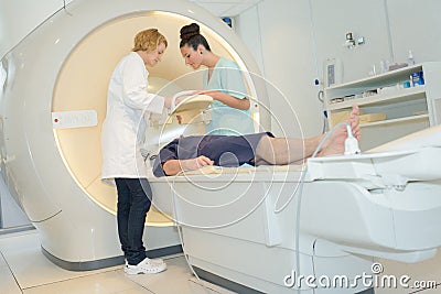 Patient on mri machine while two female doctors operating it Stock Photo