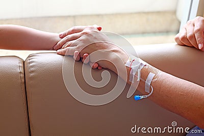 Patient`s arm with plastic infusion set and kids hand holding a patient`s hand Stock Photo