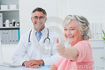 Patient showing thumbs up sign while sitting with doctor Stock Photo