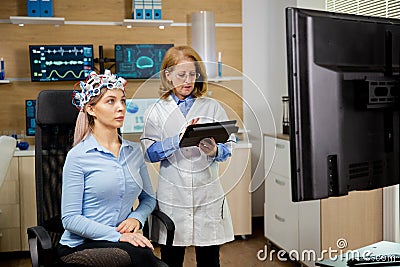 Patient woman scanning her brain and doctor making notes in the tablet holding it in her hand Stock Photo