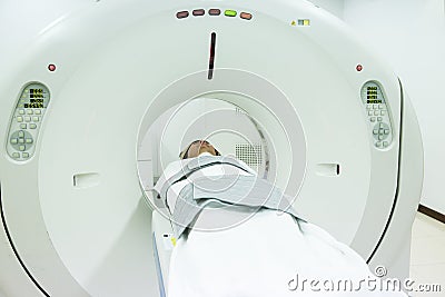 Patients screening on CT scanner. Man Undergoing CT Scan While Doctor`s Using Computers. Stock Photo