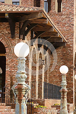 Patina green and rust white globe lampposts in front of row of orange brick arches Stock Photo