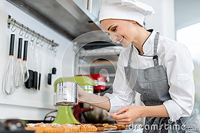 Patissier putting cocoa powder on little cakes Stock Photo