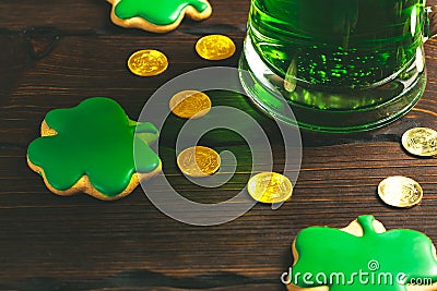 Patrick`s day background with a Glass of green beer and clover gingerbread with gold coins on wooden Stock Photo