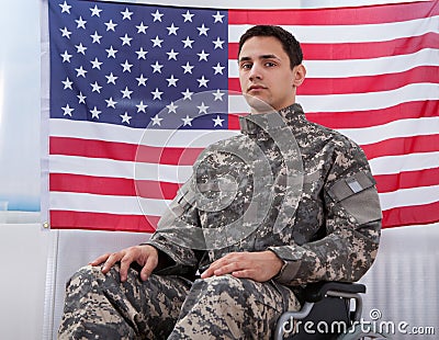Patriotic soldier sitting on wheel chair against american flag Stock Photo
