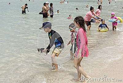 People sunbathe and swim.Some vacationers stroll along the shore Editorial Stock Photo