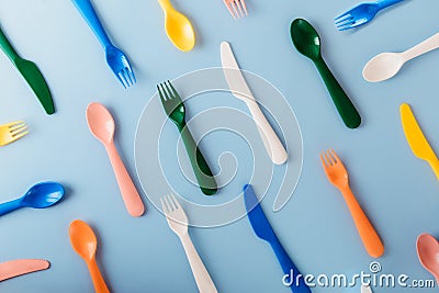 The pattern of reusable cutlery on the blue background. Plastic spoons, forks, knives top view. Summer Picnic. Plastic Stock Photo