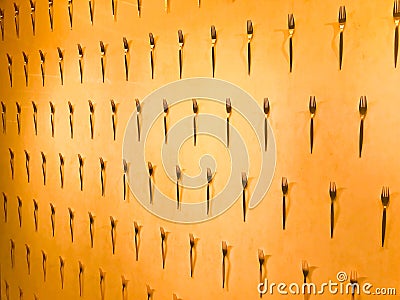 The pattern of a variety of metal forks, cutlery on the wall on a yellow background. Texture Stock Photo