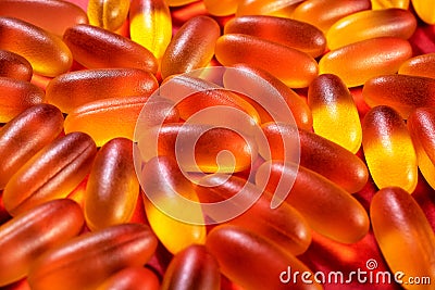 pattern of yellow gelatin capsules on a red background. omega viramins close-up macro Stock Photo
