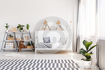 Patterned carpet and plant in white scandi bedroom interior with Stock Photo