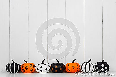 Patterned Halloween pumpkins in a row against a white wood background Stock Photo