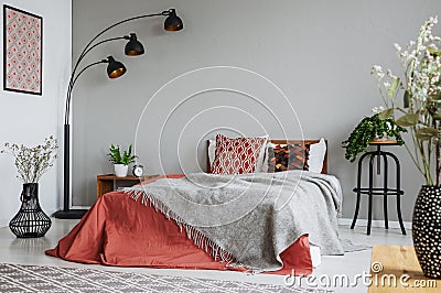 Patterned pillow and grey blanket on king size bed with dark orange duvet in luxury bedroom interior in elegant apartment Stock Photo