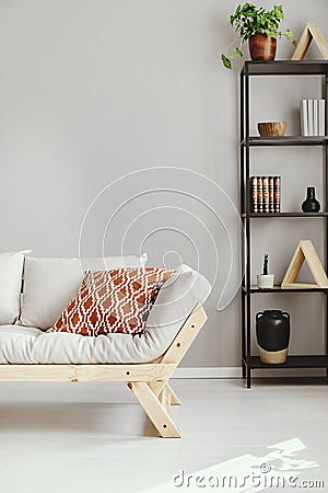 Scandinavian sofa next to shelf with different kind of accessories, real photo with copy space Stock Photo