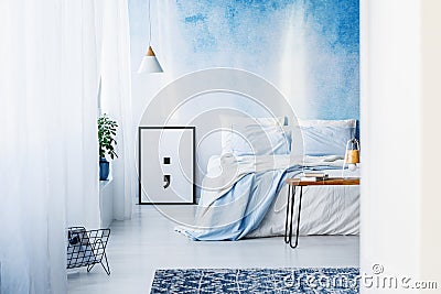 Patterned rug and poster in blue bedroom interior with bed again Stock Photo