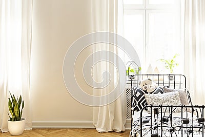 Sheets on bed in white kid`s bedroom interior with plant and copy space on the wall. Real photo Stock Photo