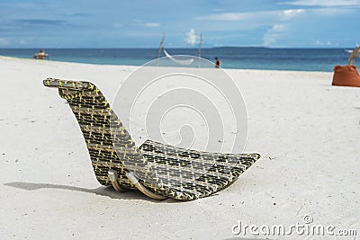 A patterned wicker chaise lounge chair right by the beachfront. At Dumaluan Beach, Panglao Island, Bohol, Philippines Stock Photo