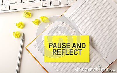 PAUSE AND REFLECT text on sticker on the diary with keyboard and pencil Stock Photo