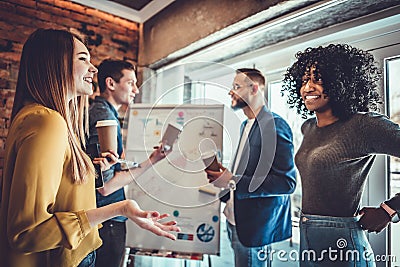 Pause for relax at work. Happy work team during break time in light modern office, talking, having drinks, smiling, all dressed in Stock Photo