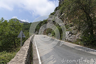 A paved road along rocky mountains with a dangerous curve. Landscape Stock Photo