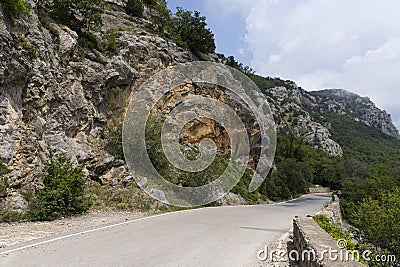 A paved road along rocky mountains with a dangerous curve. Landscape Stock Photo