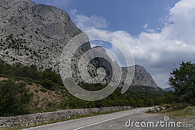 A paved road along rocky mountains with a dangerous curve. Landscape Stock Photo