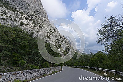 A paved road along rocky mountains with a dangerous curve. Landscape Stock Photo