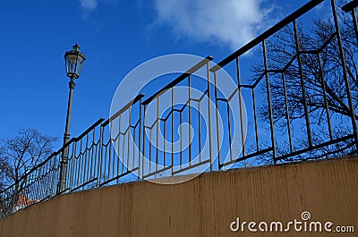 Paved sidewalk with gutter and gray metal ornate railings. lamp with glazed lampshade and black post, by old gas lamps on a city s Stock Photo