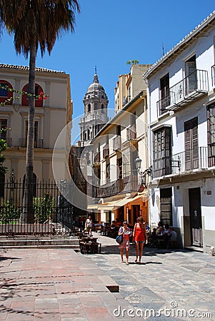 Pavement cafes along a city centre street with the Cathedral bell tower to the rear, Malaga, Spain. Editorial Stock Photo