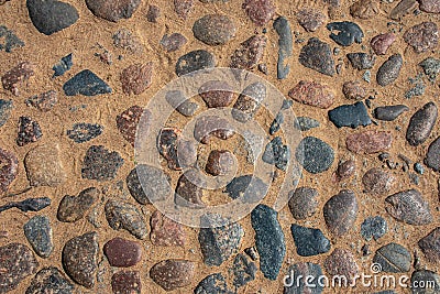 Pavement made of colored rounded stone on a sandy base Stock Photo