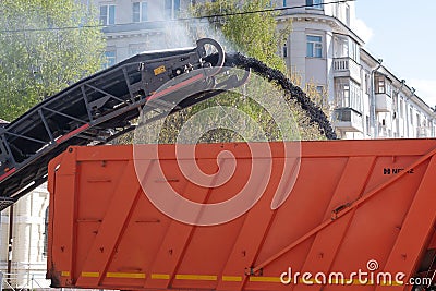 Pavement removing machine loads old asphalt into dumptruck Editorial Stock Photo