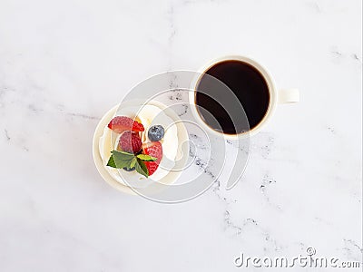 Pavlova mini cake with fruits and mint leaves and a cup with black coffee. Stock Photo