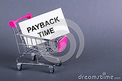 PAYBACK TIME text on sticky in mini shopping trolley Stock Photo