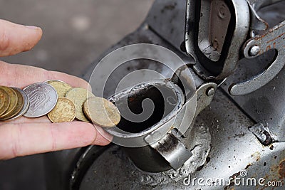 Payment for the gas, fuel, gasoline, diesel concept. Hand dropping money, coin in the can of fuel Stock Photo