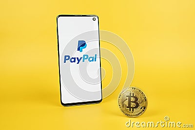 PayPal logo on smartphone and Bitcoin on yellow background Editorial Stock Photo