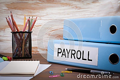 Payroll, Office Binder on Wooden Desk. On the table colored pencils, pen, notebook paper Stock Photo