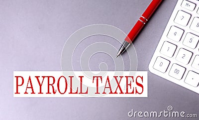 PAYROLL TAXES text written on a gray background with pen and calculator Stock Photo